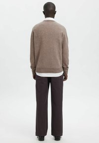 Brauner, leichter Pullover mit rundem Ausschnitt, kombiniert mit dunkelgrauen, weit geschnittenen Hosen. Glatte Textur, gerippte Bündchen und Saum.