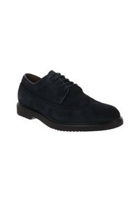 Chaussure en suede bleu foncé à lacets avec un bout arrondi, des perforations décoratives et une semelle en caoutchouc noir pour l'adhérence. Texture lisse dans l'ensemble.