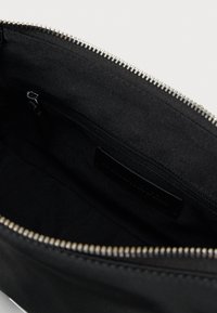 Borsa a bustina nera con zip argentata, caratterizzata da una struttura interna semplice e da un piccolo scomparto con zip. Senza marchi visibili esterni.