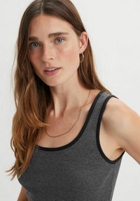 Gray ribbed tank top with a round neckline, black trim, and a textured fabric; paired with a thin gold chain necklace and hoop earrings.