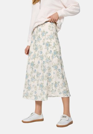 Bloemen midi rok van lichte stof, met een patroon van blauwe rozen en groene bladeren op een crèmekleurige achtergrond. Gecombineerd met witte sneakers.