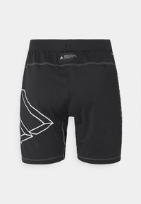 Shorts de sport noirs en tissu extensible, avec des accents géométriques blancs sur les côtés, une taille élastique et des détails de couture minimalistes.