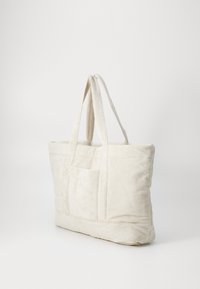 Sac fourre-tout en toile de couleur blanc cassé avec deux poignées robustes, de forme rectangulaire, surface texturée et détail de poche à l'avant.