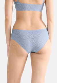 Világoskék fehérnemű szett, texturált, geometrikus mintával. A tetején és alján található hullámos szegélyek sima bélelt hatást adnak.