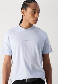 Ljusblå kortärmad t-shirt i mjukt tyg, med rundad halsringning och liten logotryck på framsidan. Enkel, rak passform.