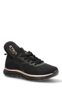 Zapatilla deportiva negra con parte superior de malla texturizada, diseño de cordones y acentos en oro rosa metálico en la suela. Estructura ligera y flexible.