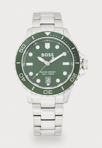 Orologio verde con cinturino in acciaio inossidabile bianco; la cassa rotonda presenta una lunetta verde, indicatori delle ore bianchi e una visualizzazione della data alle 6.