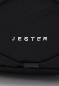 Čierny batoh s nápisom "JESTER" v bielej výšivke. Materiál sa zdá byť odolná tkanina s textúrovaným povrchom.