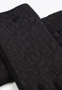 Černá prošívaná látka s reliéfním vzorem textu. Disponuje černými kovovými doplňky, hladkou texturou a pevnou strukturou.