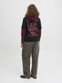 T-shirt noir avec un graphique de bol de ramen rouge, porté sous un hoodie bourgogne. Assorti avec un jean gris ample et des bottines noires.