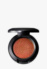 Compact de maquillage rond avec un couvercle noir laqué, contenant une poudre orange brûlée scintillante. La texture semble finement moulue avec une finition granuleuse.