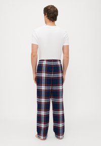 Herre bomull pysjamasbukser i marineblå og hvit rutete mønster, med elastisk liv og løs passform. Kombinert med en ensfarget hvit t-skjorte.