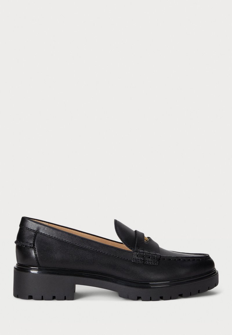 Mocassin en cuir noir avec semelle crantée épaisse, petit talon bloc et une bride décorative sur le dessus, présenté de profil.