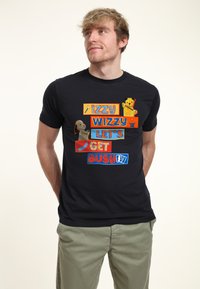 Sort kortærmet t-shirt med farverige grafik, der siger "IZZY WIZZY LAD OS BLIVE BESKÆFTIGE", med tegneseriefigurer og legende elementer.