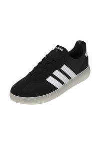 Scarpa da ginnastica nera con tomaia in tessuto liscio, tre strisce bianche, suola in gomma grigio chiaro e logo nero sulla linguetta.