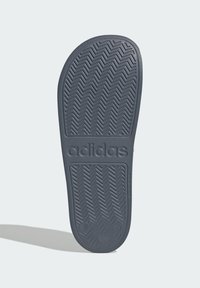 Podeszwa buta Adidas z teksturowanej szarej gumy w wzór jodełki i wytłoczonym logo, zaprojektowana z myślą o przyczepności i trwałości.