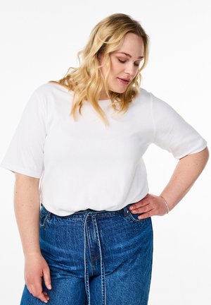 Haut blanc à rayures avec des manches courtes associé à un jean bleu taille haute avec un détail à nouer à la taille. Design et texture simples.