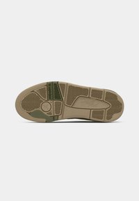 Sneaker zole bēšā gumijā ar zaļu akcentu. Iezīmē herringbone un apaļas velcēšanas formas labākai saķerei.
