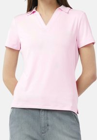 Camisa polo rosa con escote en V, mangas cortas y una textura suave. Presenta un diseño clásico con aberturas laterales en el dobladillo para mayor comodidad.