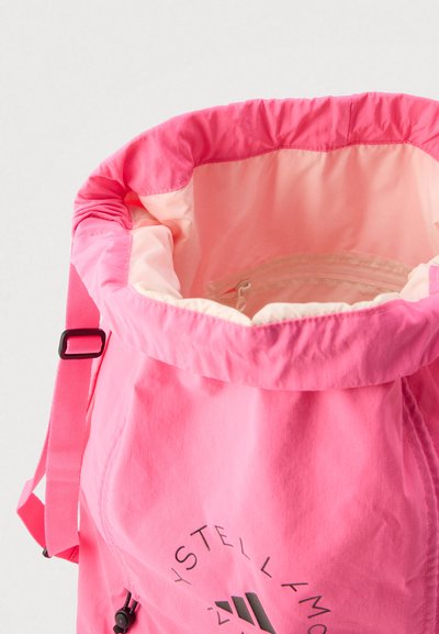 Ροζ σακίδιο πλάτης με κορδόνι, που έχει εξωτερικό μέρος με απαλή υφή, ευρύχωρο εσωτερικό με τσέπη με φερμουάρ και λεπτομέρειες με λογότυπο στο μπροστινό μέρος.