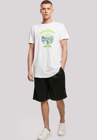 Hvit bomulls t-skjorte med et fargerikt "Rick and Morty"-grafikk. Kombinert med svarte treningsshorts og hvite joggesko. Enkel design, avslappet passform.