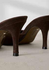 Rudos suede aukšti batai su apvalia nosimi, elegantiškas siluetas ir juodos spalvos kulno akcentas. Texture paviršius ir subtilūs dizaino ypatumai.