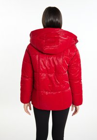 Rød pufferjakke med hætte, der har en glat overflade, quiltet design og indsnævret talje bagpå, set fra bagsiden.