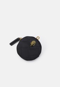 Svart, rund påse med kviltat mönster; har en guldfärgad snäcka som accent och en svart dragkedjehandtag. Tillverkad av mjukt tyg.