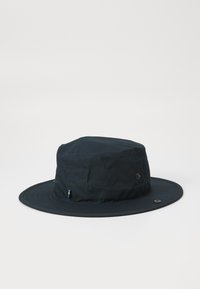 Tmavě modrý klobouk typu bucket vyrobený z lehké tkaniny, s širokým okrajem, jemnými švy a malou akcentní nášivkou.