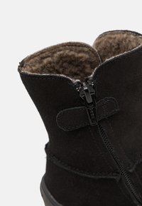 Czarne zamszowe botki za kostkę z zapięciem na zamek, miękkim futerkiem w środku oraz detalami w postaci ściegów, z okrągłym noskiem i płaską gumową podeszwą.