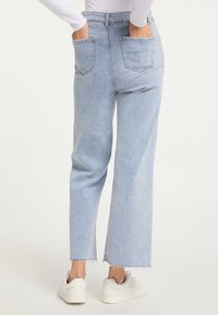 Jeans decolorate, cu talie înaltă și picior drept, având două buzunare pe spate și margini despicăte. Purtați cu adidași albi.