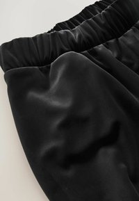 Sort satin stof med en glat tekstur og en gathered talje. Designet har flydende draperinger og bløde konturer.