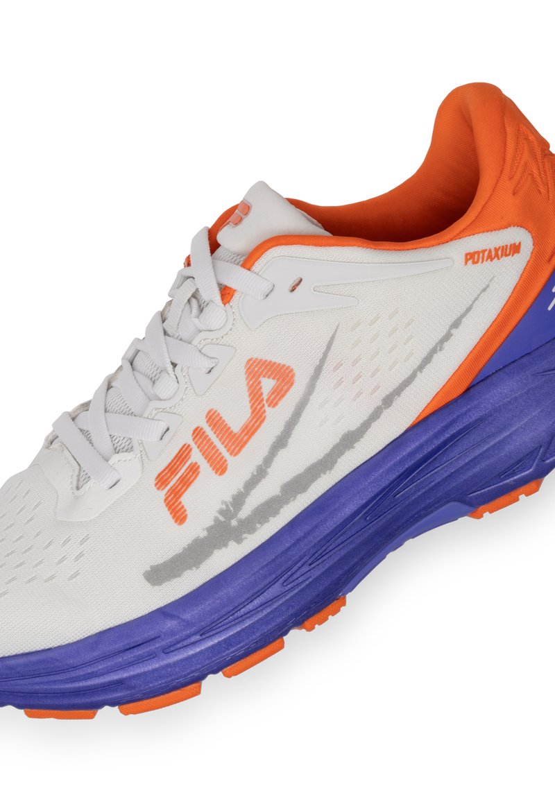Zapato de running blanco con acentos en naranja y púrpura. Presenta una parte superior de malla, suela acolchada y un destacado logo de Fila en el lado. Detalles texturizados presentes.