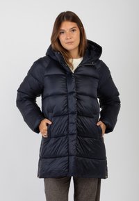 Giacca a soffietto blu navy con design trapuntato, cerniera anteriore e cappuccio attaccato. Presenta tasche laterali e un taglio leggermente più lungo per una maggiore copertura.