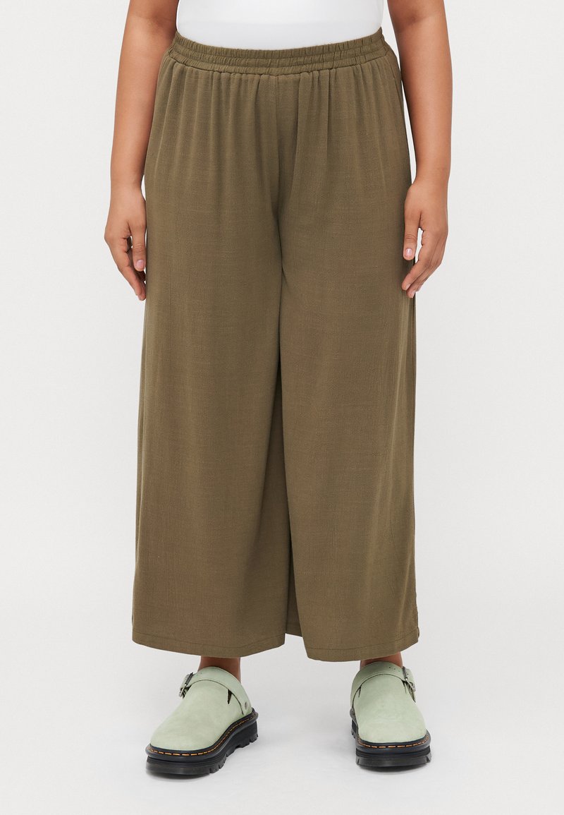 Olive green wide-leg pants made from soft fabric, featuring an elastic waistband. Worn with light green clogs.