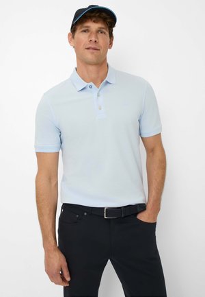 Hellblaues Poloshirt mit kurzen Ärmeln und Kragen, kombiniert mit schwarzen Hosen und einem strukturierten schwarzen Gürtel. Lässiges Design mit Knöpfen am Hals.