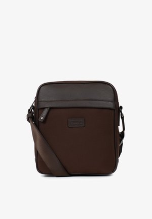 Sac bandoulière carré marron foncé avec poche zippée à l'avant, sangle réglable et accents en cuir sur le dessus et les bords.