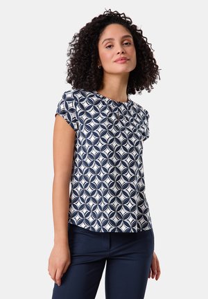 Short-sleeve blouse made of lightweight fabric, featuring a navy and white geometric pattern with a keyhole detail at the neckline.