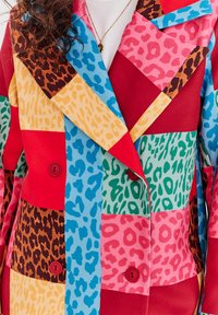 Farebný patchwork blejzer s leopardími vzormi, v červenej, ružovej, zelenej, žltej a modrej farbe, s dvoma gombíkmi a širokým golierom.