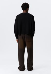 Μαύρο καλλιεργημένο πουλόβερ με ριμπ τελείωμα, συνδυασμένο με καφέ παντελόνια με διαβάθμιση χρώματος και πίσω τσέπη. Ομαλή υφή και άνετη εφαρμογή.