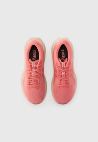 Baskets de sport rose clair avec une tige en tricot texturé, un col rembourré et une semelle en caoutchouc beige. Dispose de lacets et d'un logo sur la languette.