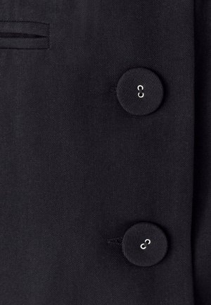 Black fabric coat featuring a smooth texture, a single chest pocket, and two round buttons with a silver loop detail.