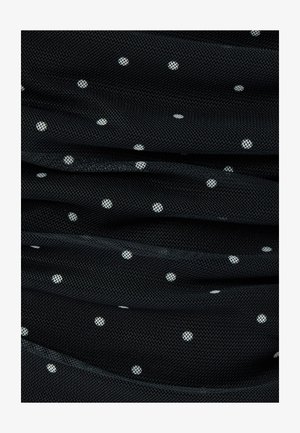 Tessuto a rete nero con pois bianchi, caratterizzato da una superficie testurizzata e pieghe drappeggiate, creando profondità e interesse visivo.