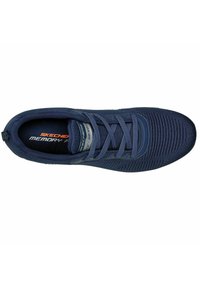 Dunkelblaue Skechers-Sneaker mit einem gestrickten Obermaterial, strukturiertem Design, Schnürsystem und einer Memory-Schaum-Einlegesohle. Mit einem Logo an der Seite.