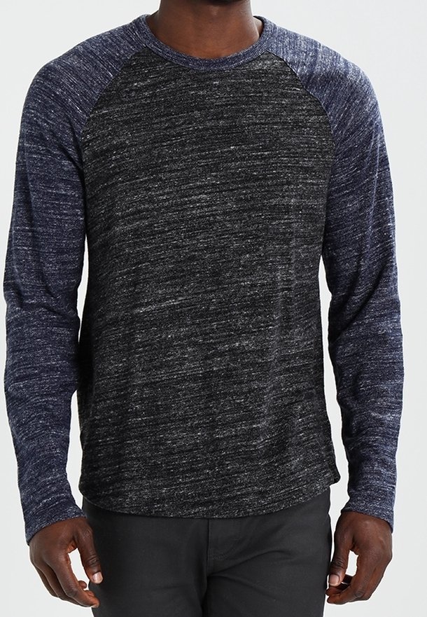 Chemise à manches longues avec un corps gris foncé texturé et des manches raglan bleu marine. Matériau léger semblable à du tissu avec une coupe décontractée.