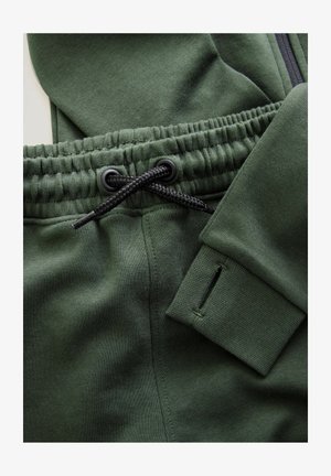 Zelene dukserice s teksturiranim pojasom i crnom vezicom, bočnim džepom i glatkom završnom obradom.