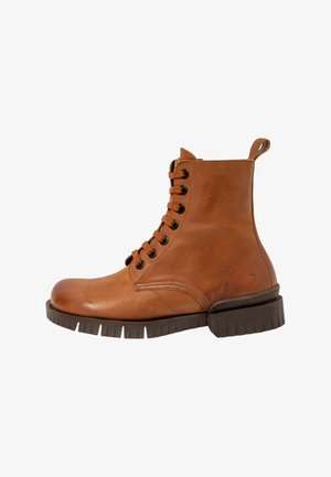 Brune læder ankelstøvle med rund tå, snørebånd foran, tekstureret overflade og kraftig sål med mønster. Har en strop bagpå.