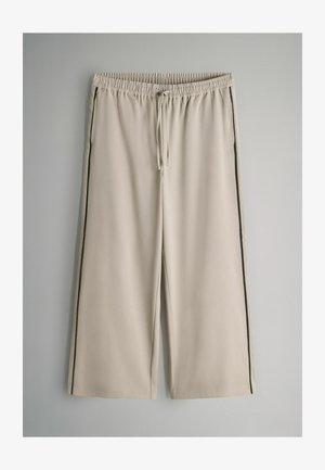 Beige sweatpants met een elastische tailleband en trekkoord, voorzien van zwarte zijkanten en een ontspannen pasvorm. Glad textuur en lengte tot halverwege de kuit.