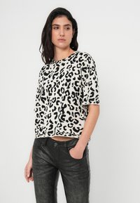 Πουκάμισο με κοντό μανίκι και λεοπάρ σχέδιο σε μπεζ και μαύρο, υφασμάτινο με υφή, άνετη εφαρμογή, σε συνδυασμό με μαύρο ψηλόμεσο παντελόνι με υφή.