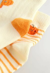 Yellow socks with orange accents; one features a pattern of a small animal face, the other has horizontal stripes in orange and yellow.
